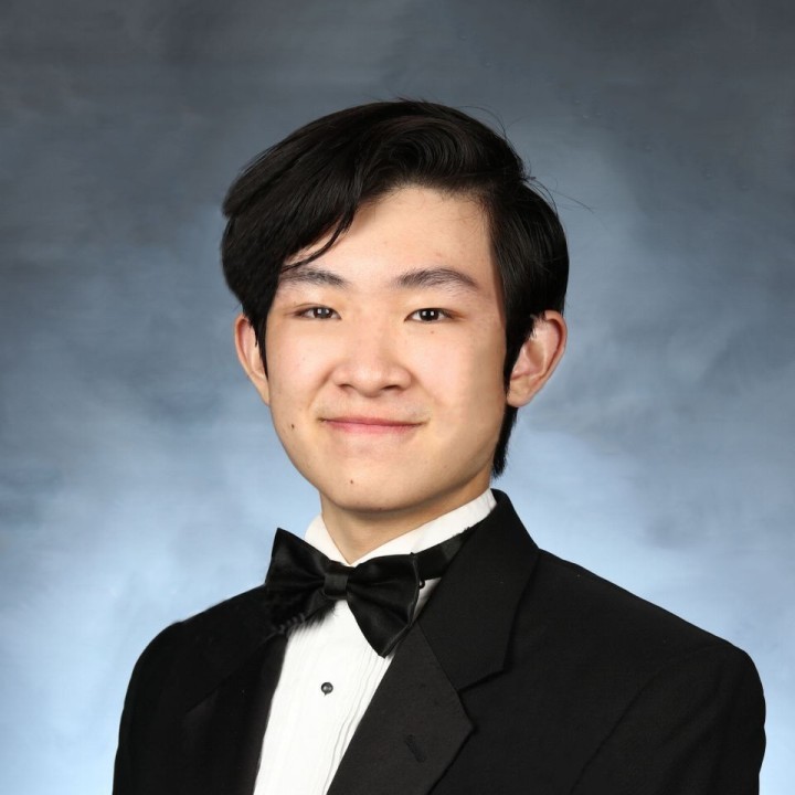 A portrait of me, Hamilton Wang, taken when I was a senior in high school. I'm wearing a black suit and bowtie and my hair is combed up neatly. I'm in front of a blue-gray backdrop.